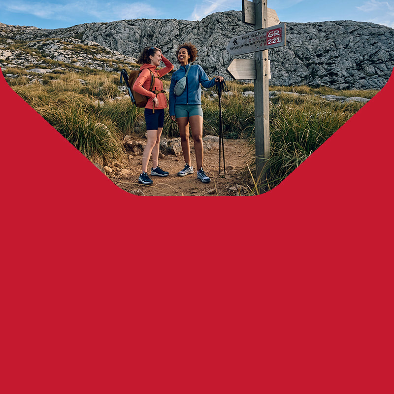 Drie wandelaars met rugzakken en stokken beklimmen een rotsachtig bergpad in de Alpen. De zon schijnt op het landschap. Het berglandschap is indrukwekkend.