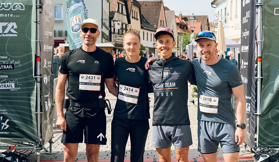 Vrouwelijke agent in witte GLB en Salomon-vest, die in openlucht glimlachen.