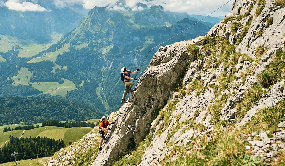 Mountaineer laces up mountain boots with headlamp, rope and helmet.