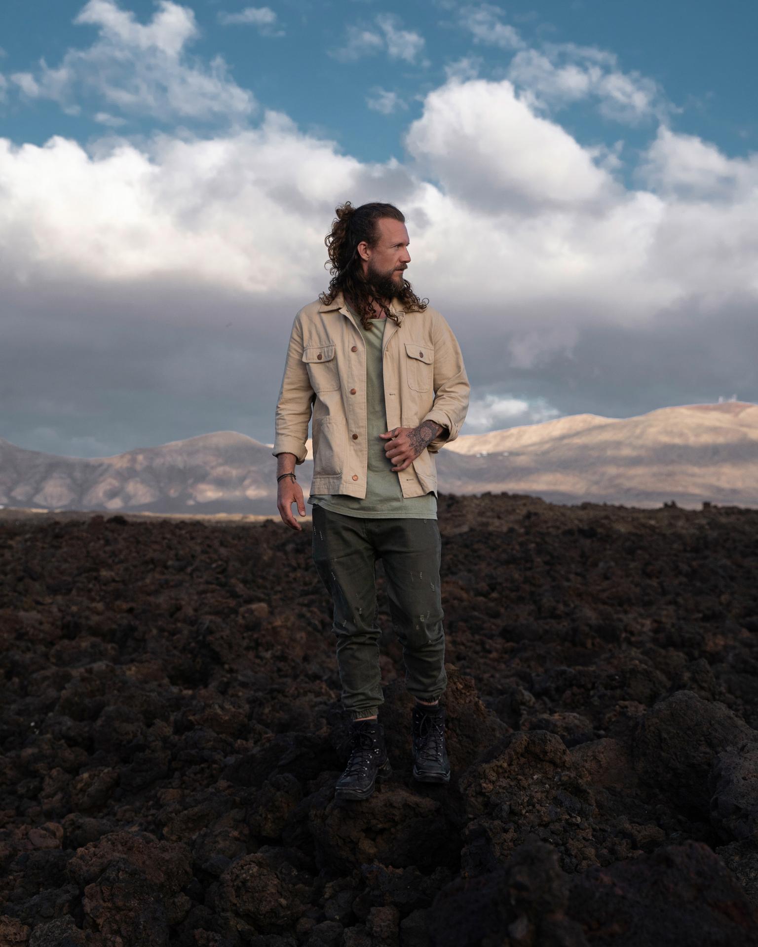 Mann mit langen Haaren klettert auf einem Felsen mit Blick aufs Meer.