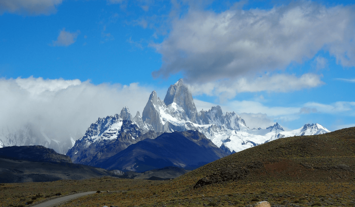 Snow-capped mountains in the Fitz Roy massif, Argentina, under blue skies with clouds.