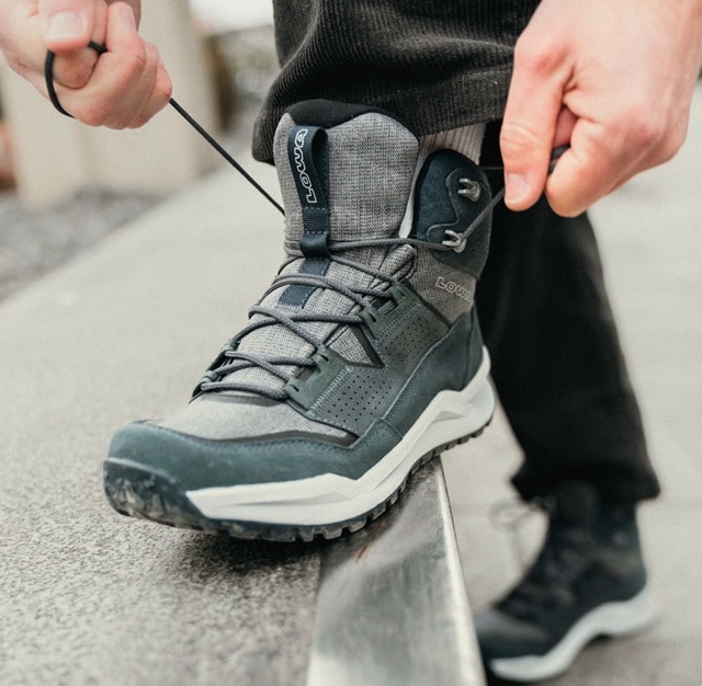 Die leuchtend blauen Wanderschuhe einer Person stehen auf einem Felsen und präsentieren Outdoor-Ausrüstung in einer natürlichen Umgebung.