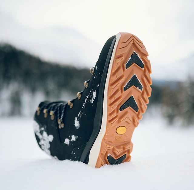 Le scarpe da trekking blu brillante di una persona sono appoggiate su una roccia e presentano l\'attrezzatura outdoor in un ambiente naturale.