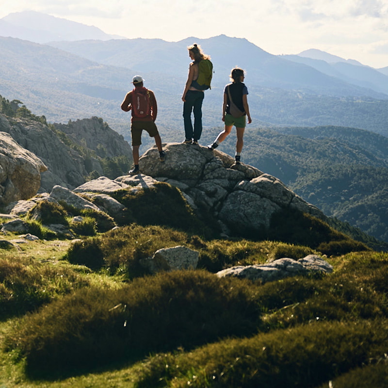 Three people hiking on a rock in a mountain landscape