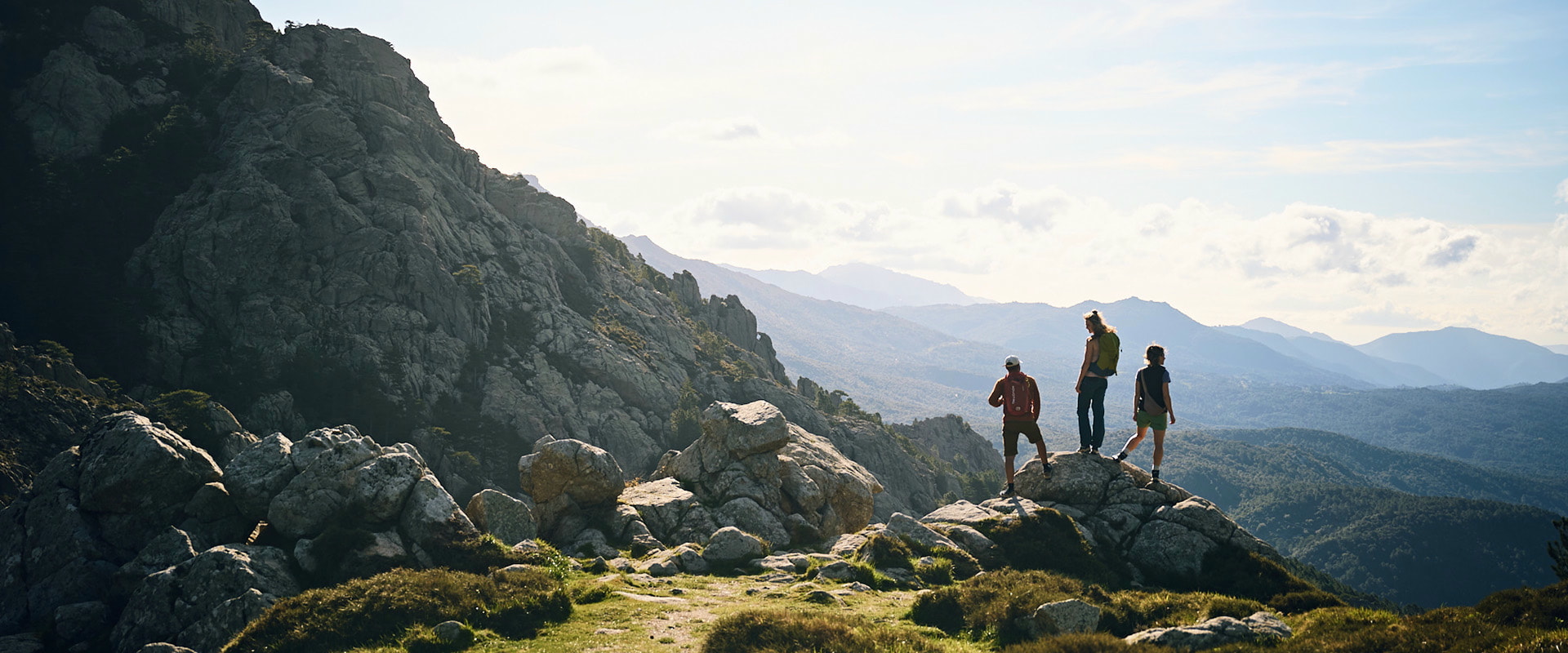 Three people hiking on a rock in a mountain landscape