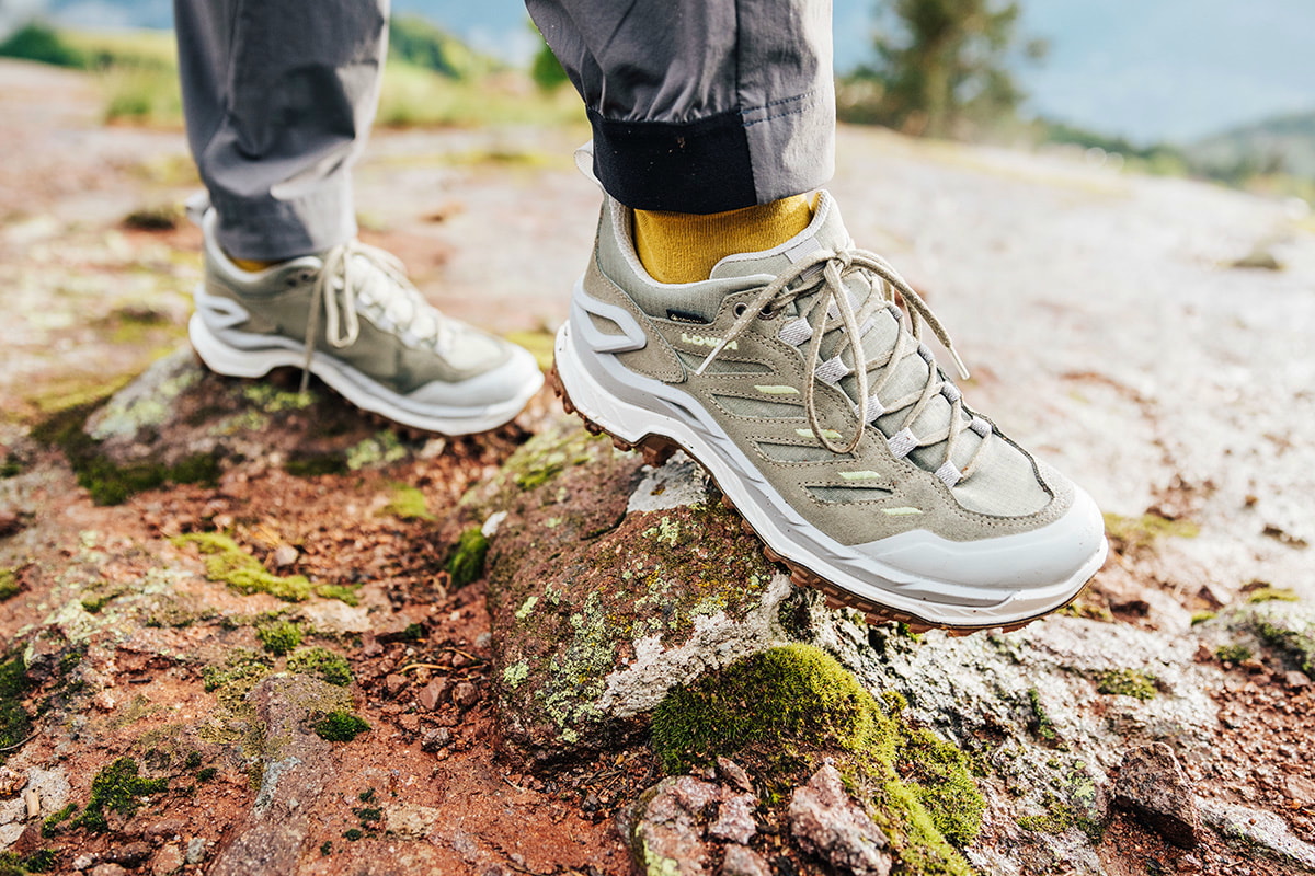 Close-up of a lightweight hiking boot on a rock, with short socks and legs.