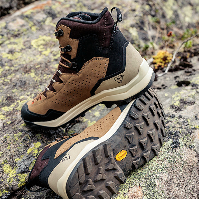 Ein Paar braune Wanderschuhe liegen auf einem moosbewachsenen Felsen.