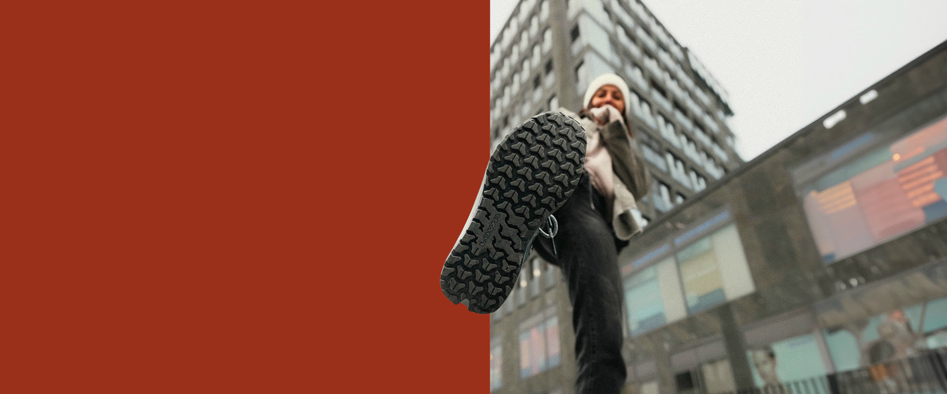 The image shows a person stepping forward wearing LOWA shoes. A building can be seen in the background.