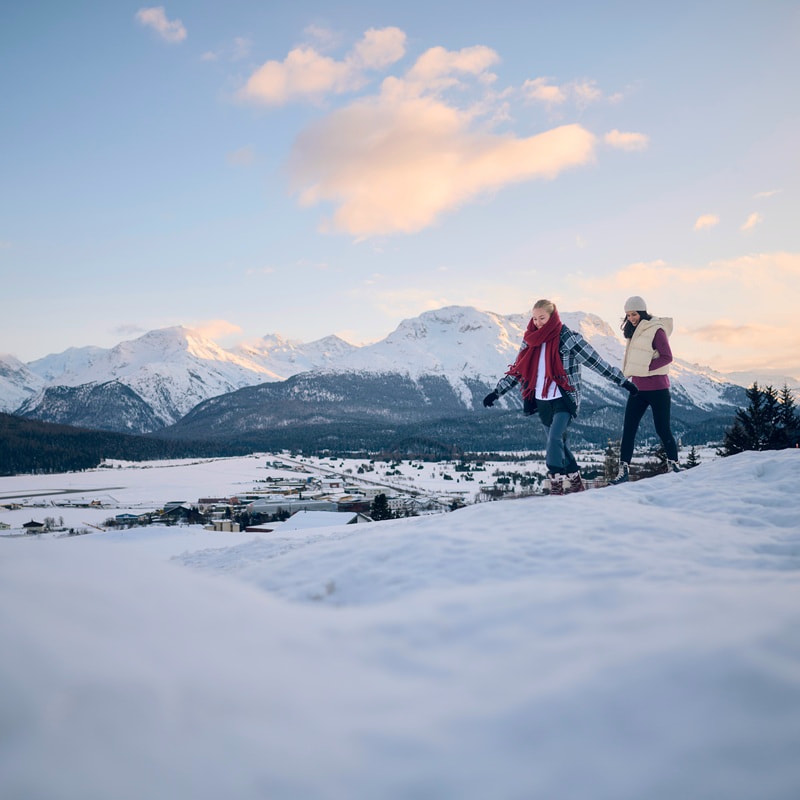 Two female hikers and one male hiker with backpacks are climbing a rocky mountain trail.