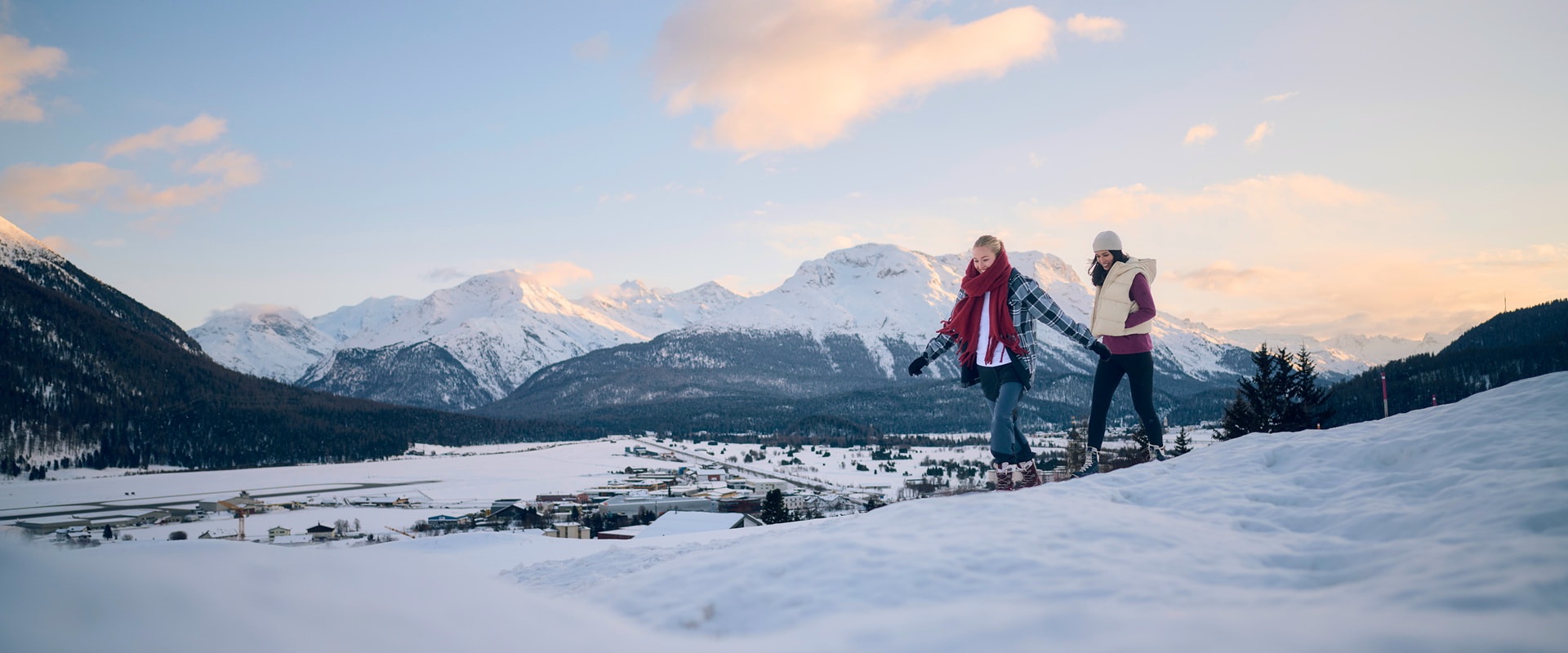 Two female hikers and one male hiker with backpacks are climbing a rocky mountain trail.