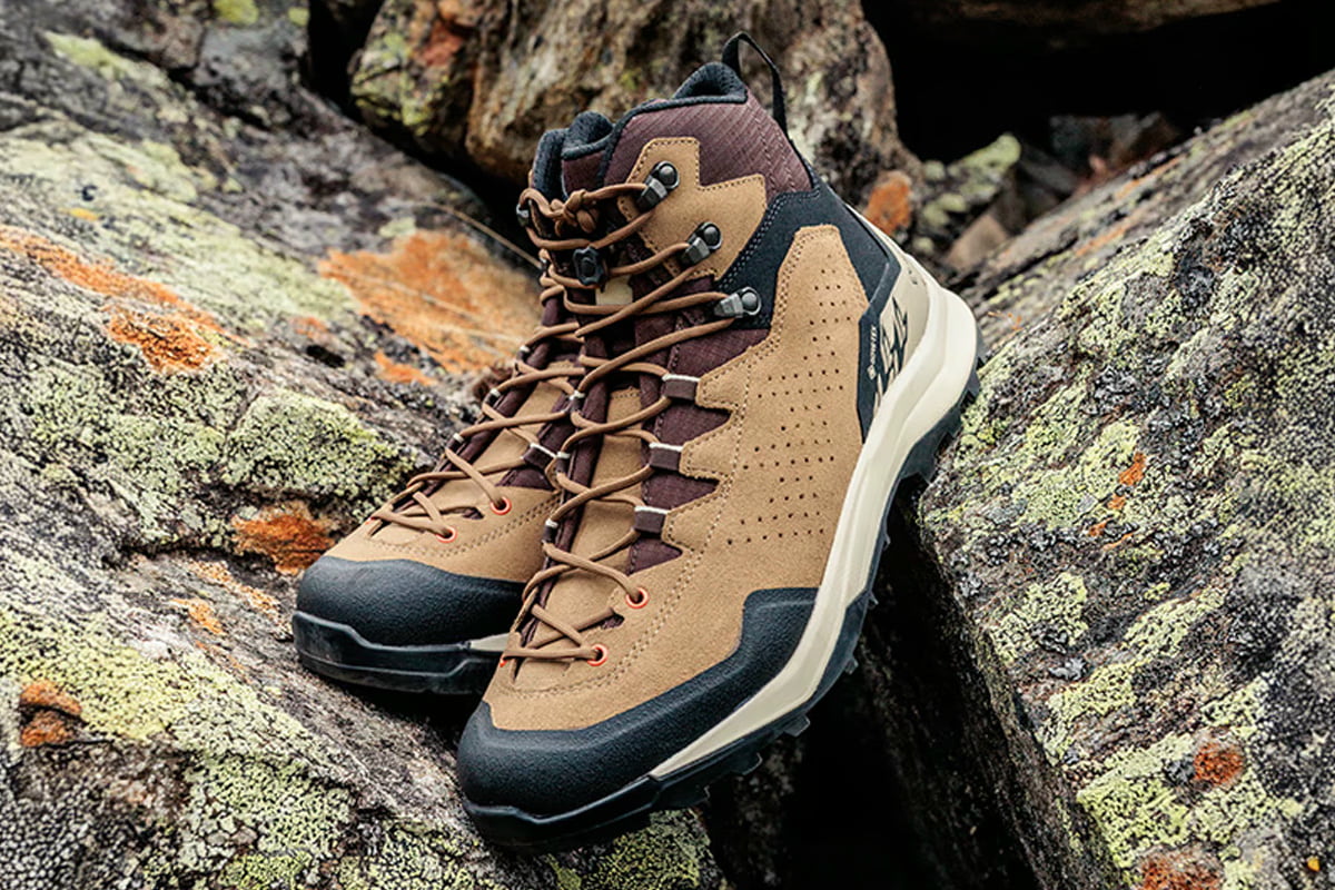 Fotografie eines braun-schwarzen Wanderschuhs auf felsigem Untergrund, der robuste Bauweise und Profilsohle für Outdoor-Aktivitäten zeigt. Details wie Metallösen, gepolsterter Schaft und markantes Sohlenprofil heben Funktionalität und Strapazierfähigkeit hervor.