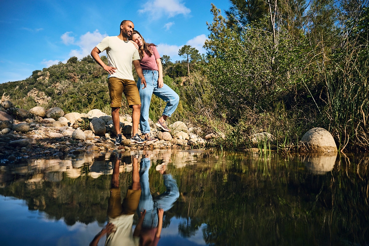Gruppe beim Wandern auf einem schmalen Pfad in einem Wald, umgeben von Bäumen und Gebüsch.