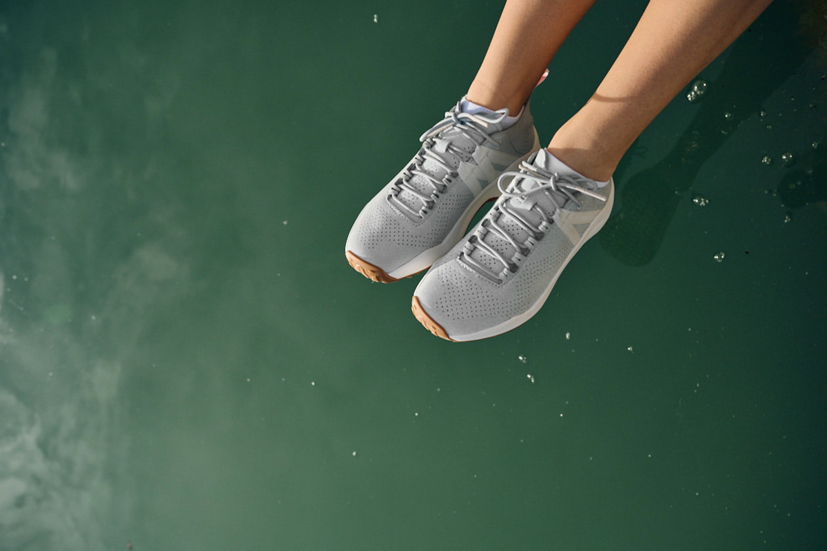 Aktive Person trägt Wanderschuhe auf einem felsigen Pfad, umgeben von Natur.