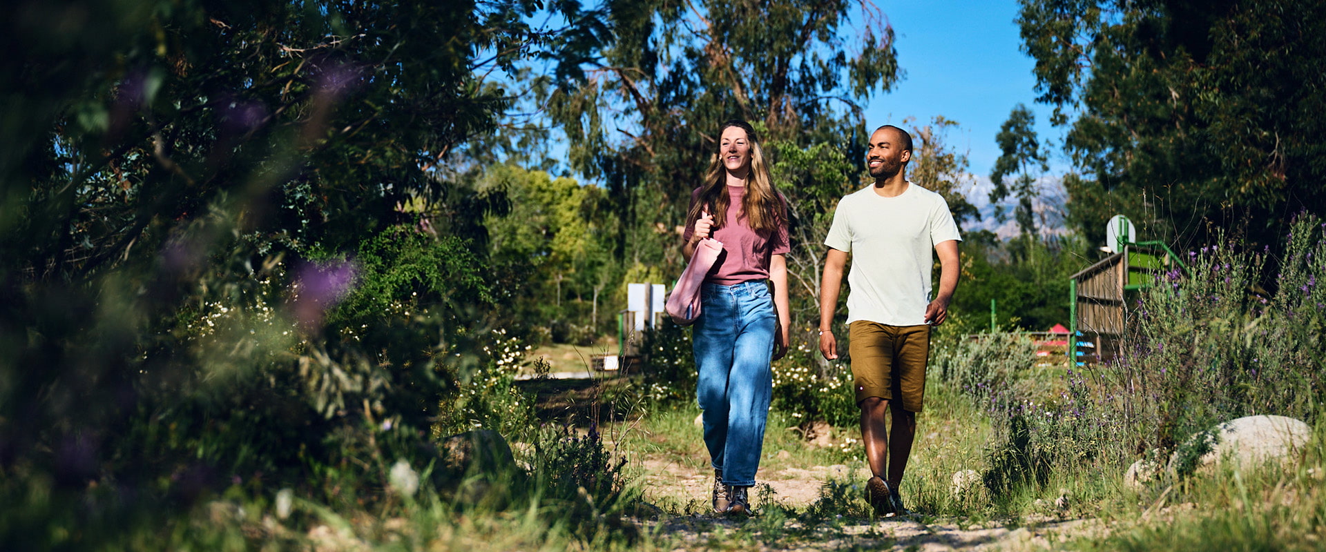 Ein Mann und eine Frau spazieren auf einem Feldweg in sommerlicher Atmosphäre.