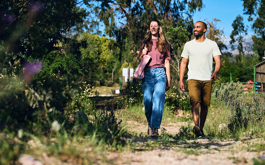 A man and a woman are walking along a dirt road in a summery atmosphere.