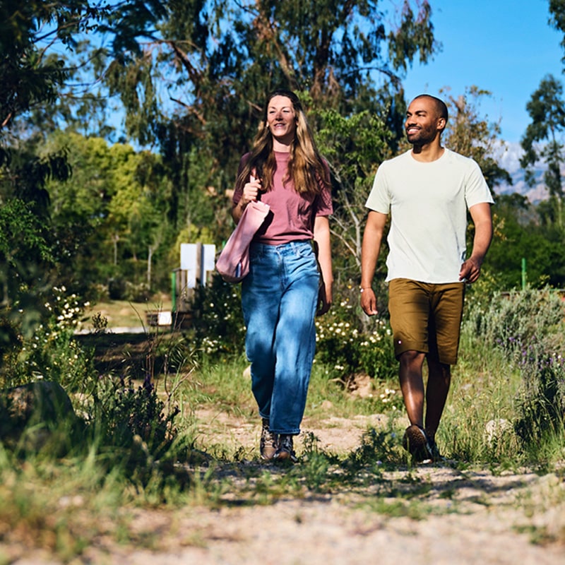 Ein Mann und eine Frau spazieren auf einem Feldweg in sommerlicher Atmosphäre.