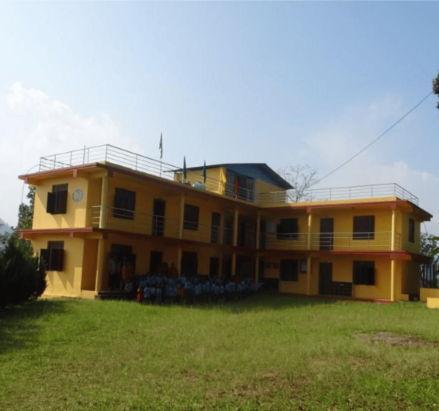 Yellow school building with several floors in front of a lawn with a group of children.