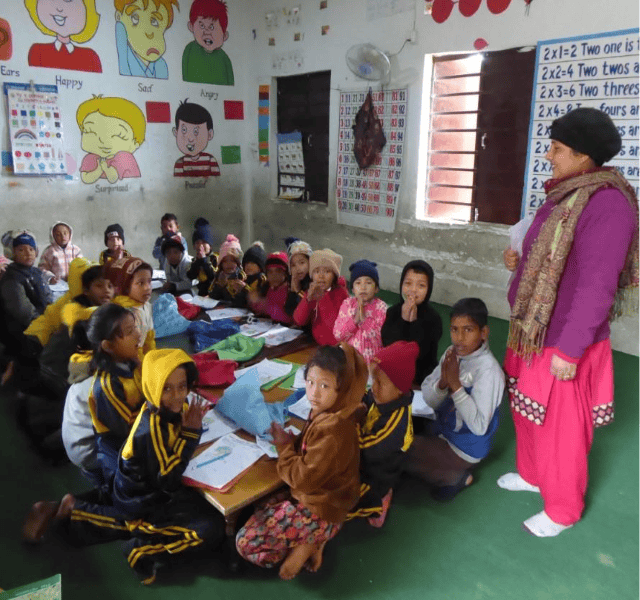 Classroom with children sitting in front of a teacher and learning.