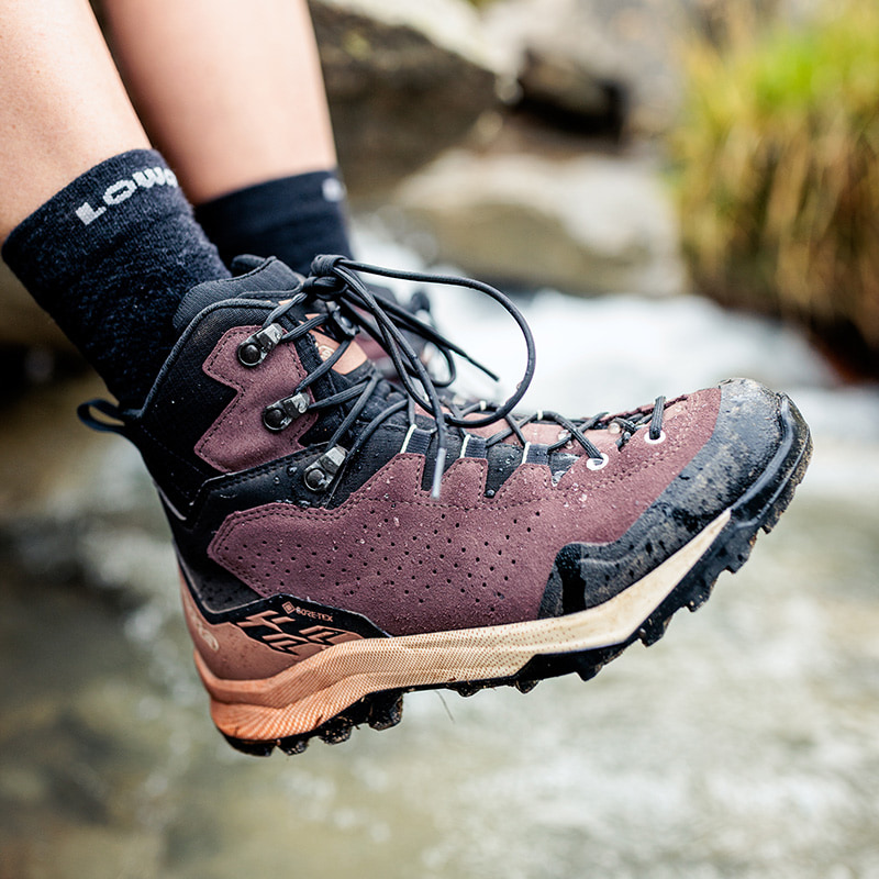 Chaussure de randonnée LOWA EXPLORER GTX MID en utilisation près d\'un ruisseau de montagne.