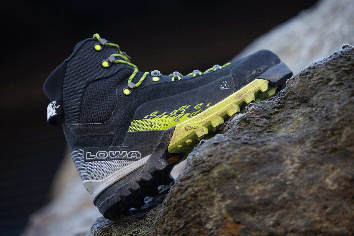 Nahaufnahme eines schwarz-gelben CERVINO GTX MID, der steil am Felsen steht.