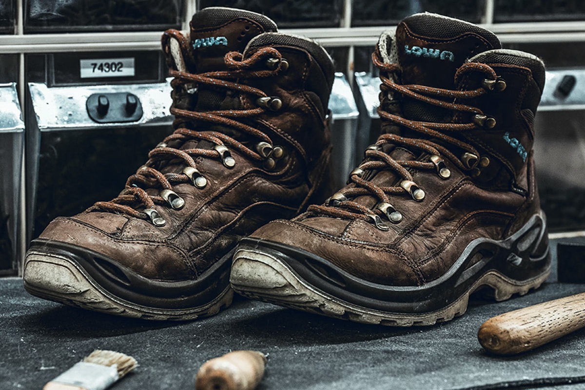 Ein Paar gebrauchte braune LOWA Wanderschuhe auf einer Werkbank